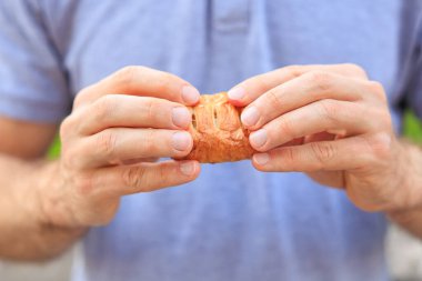 Bir adamın eli peynirli, abur cuburlu ve fast food konseptli mini puf böreği tutar. Bulanık arkaplan ve metin için kopyalama alanı olan ellere seçici odak.