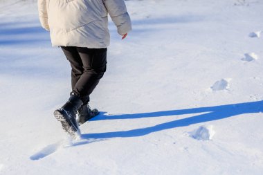 Karda yürüyen, kışlık çizmeli kadın bacakları. Seçici odaklı arkaplan ve metin için alanı kopyala