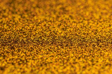 Görüntü, altın parıltılı bir yüzeye yakındır. Altın rengi çok parlak ve parlak. Lüks ve göz alıcı bir dokuya benziyor.
