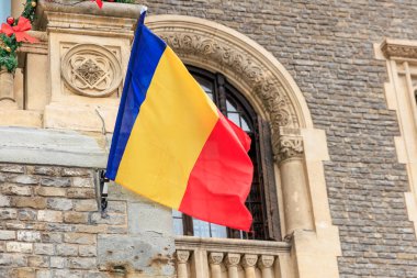 Romen bayrağı kemerli pencereli tarihi taş binada dalgalanıyor.