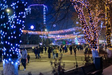 Renkli tatil ışıkları ve kalabalıkla dolu bir gece şehir caddesi. 20 Aralık 2024 Balti Moldova.