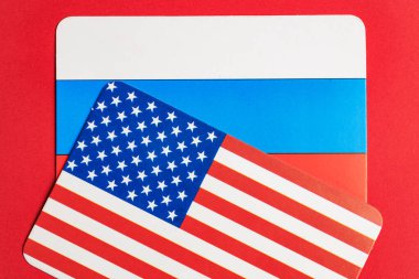 Uluslararası ilişkileri vurgulayan kırmızı arka planda Rus ve Amerikan bayrakları.