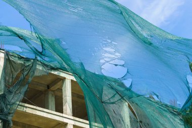 Kasırga rüzgarı tarafından yırtılan iskelelerde koruyucu ağ. Seçici odaklı arkaplan ve metin için alanı kopyala.