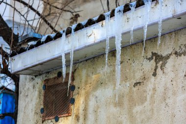 Çatıdaki büyük buz saçakları yoldan geçenler için tehlike arz ediyor. Seçici odaklı arkaplan ve metin için alanı kopyala