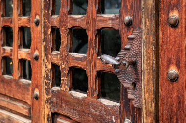 Demir sapı ve cam panelleri olan ahşap bir kapı..