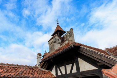 Mavi gökyüzü altında kırmızı kiremitleri ve çapraz şekilli yapısı olan tarihi Avrupa çatısı.