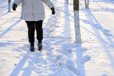 Karda yürüyen, kışlık çizmeli kadın bacakları. Seçici odaklı arkaplan ve metin için alanı kopyala