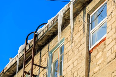 Çatıdaki büyük buz saçakları yoldan geçenler için tehlike arz ediyor. Seçici odaklı arkaplan ve metin için alanı kopyala