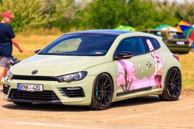 Side view of a customized Volkswagen Scirocco featuring unique anime-themed artwork on the doors, giving it a distinct and creative look. July 2, 2023 Liadoveni Moldova. clipart