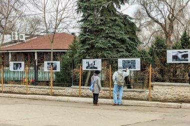 Açık hava fotoğraf sergisi yaşlı beyaz erkek ve kadın tarafından izleniyor. 3 Ocak 2024 Balti Moldova.