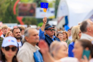 Kalabalığın içinde mavi bayrak taşıyan bir adam. Kalabalık çok farklı ve adam ilgi odağı, Avrupa Günü 'nü kutluyor. 19 Mayıs 2024 Balti Moldova