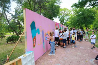 Toplum sanatı etkinliği: çeşitli çocuklar ve yetişkinler parkta grafiti yapıyor. 31 Mayıs 2024 Balti Moldova.
