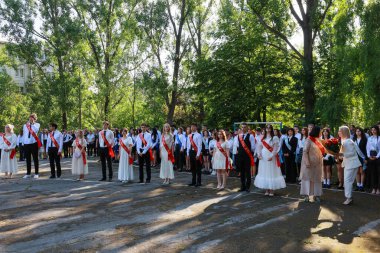 Mezuniyet töreni, açık havada resmi giyinmiş genç yetişkinlerle birlikte. 31 Mayıs 2024 Balti Moldova.