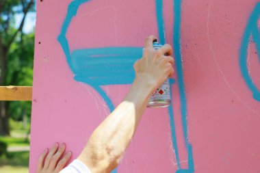 Açık havada mavi sprey boyayla pembe duvara el yazısı çiziyorum. 31 Mayıs 2024 Balti Moldova.