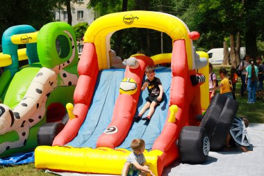 Genç beyaz çocuklar açık hava parkında şişme kaydırağın keyfini çıkarıyorlar. 31 Mayıs 2024 Balti Moldova.