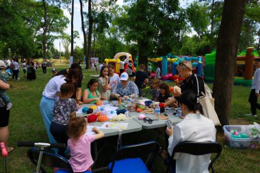 Outdoor family craft event with women and children engaged in creative activities. May 31, 2024 Balti Moldova. clipart