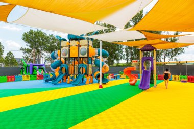 Büyük mavi slaytlı ve sarı slaytlı bir oyun alanı. Bir kadın oyun alanının yanından geçiyor. 8 Haziran 2024 Balti Moldova