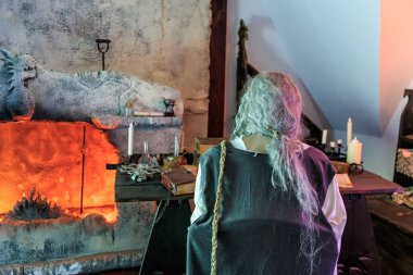 Yaşlı beyaz erkek taş ejderha heykeliyle tarihi bir ortamda.