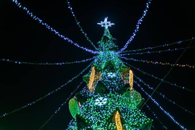 Yıldızlı gece gökyüzü ve şenlikli süslemeleriyle aydınlatılmış Noel ağacı.