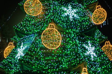 Geceleyin ışıl ışıl süsleri ve kar taneleri olan canlı bir Noel ağacı..