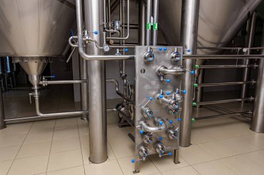 Bira fabrikasında paslanmaz çelik bira fermantasyon tankları ve borular..