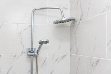 Mermer döşeli banyo köşesinde modern duşun başlığı..