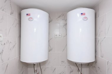 Çift Amerikan görünümlü beyaz su ısıtıcıları fayanslı bodrum odasında..