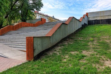 Yeşil duvarı olan bir binaya çıkan bir merdiven. Merdivenler betondan yapılmış ve kahverengidir. Merdivenler çok dik ve duvar çok yüksek.