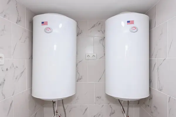 Çift Amerikan görünümlü beyaz su ısıtıcıları fayanslı bodrum odasında..