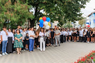 Farklı yetişkinler ve gençlerin renkli balonlar tuttuğu açık hava okul etkinliği. 2 Eylül 2024 Balti Moldova.