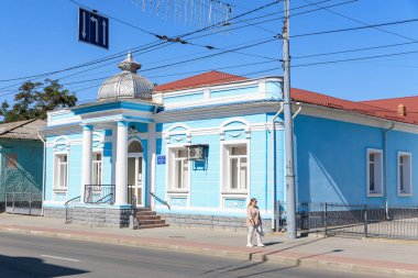 Güneşli caddede kubbeli ve çitli tarihi mavi bir bina. 9 Eylül 2024 Balti Moldova.