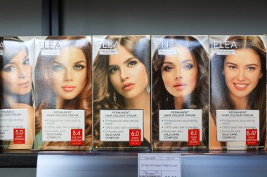 Kalıcı saç kremi kutuları ve sarışın ve esmer gözlüklü kadın modeller. 18 Eylül 2024 Balti Moldova.