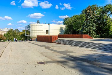 Beyaz cepheli ve kırmızı çatılı büyük bir bina. Bina ağaçlarla çevrili ve ona uzanan büyük bir merdiveni var. Sahne huzurlu ve huzurlu. 25 Eylül 2024 Balti Moldova