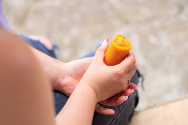 Doğal balmumundan yapılmış el yapımı mum bir kadının ellerinde kalp şeklinde.