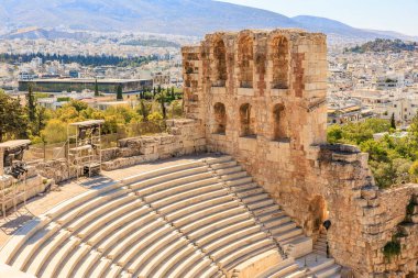 Büyük bir taş kemer yolu ve taş bir balkonu olan taş bir bina. Binanın etrafı ağaçlarla çevrili ve Atina Akropolü kenti manzaralı