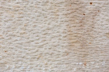 Textured beige stone wall with worn patterns and natural irregularities. clipart