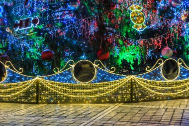 Işıkları ve süslemeleri olan bir Noel ağacı. Işıklar parlak ve renkli, neşeli ve neşeli bir atmosfer yaratıyor.