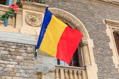 Romen bayrağı taş ve tuğla cepheli tarihi Avrupa binasına dalgalanıyor.