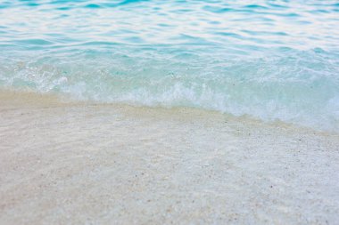 Okyanus sakin ve su berrak. Kum beyaz ve dalgalar küçük