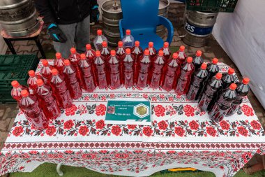 Açık hava pazarında renkli şaraplar çiçek masa örtüsünde sergilenir. 15 Şubat 2024 Balti, Moldova.