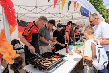 Alman gönüllüler 19 Mayıs 2024 'te Balti Moldova' da Avrupa Günü 'nde ızgara sosis pişiriyor ve otantik Alman mutfağını ziyaretçilerle paylaşıyor.