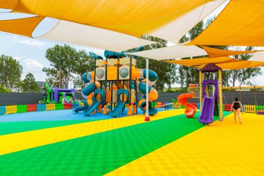 Üzerinde sarı ve mavi bir gölgelik olan bir oyun parkı. Bir çocuk oyun alanında yürüyor. Oyun alanı renkli ve eğlenceli bir atmosferi var. 8 Haziran 2024 Balti Moldova