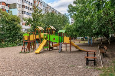 Şehir parkı ortamında sarı ve yeşil slaytlı renkli oyun alanı. 30 Haziran 2024 Balti Moldova.