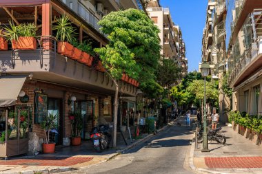 Kaldırımda mavi bir tabela olan bir cadde. Kaldırımda ve sokakta birkaç saksı bitkisi var. 8 Ağustos 2024 Selanik Yunanistan