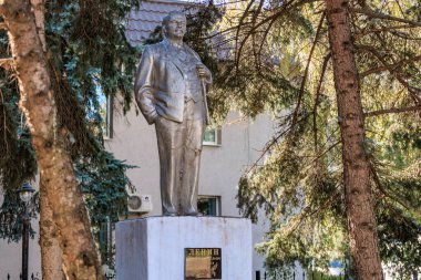 Ağaçlarla çevrili tarihi erkek figürünün bronz heykeli, Lenin. 13 Ekim 2024 Basarabeasca Moldova.