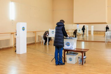 Beyaz yetişkinler oy sandığıyla kapalı alanlarda oy veriyorlar. 20 Ekim 2024 Balti, Moldova.