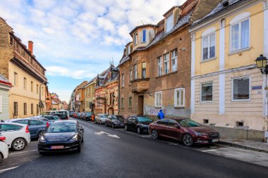 Birkaç araba ve kamyonla dolu işlek bir cadde. Cadde binalarla dolu ve çok trafik var. 14 Aralık 2024 Brasov Romanya