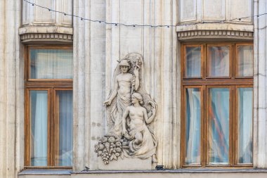 Üzerinde iki kadının heykeli olan bir bina. Heykel, kucağında çocuk tutan bir kadının heykeli. Binanın bir sürü penceresi ve bir balkonu var. 14 Aralık 2024 Brasov Romanya