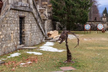 Metal sculpture of a dragon is standing in a grassy field. December 15, 2024 Busteni Romania. clipart