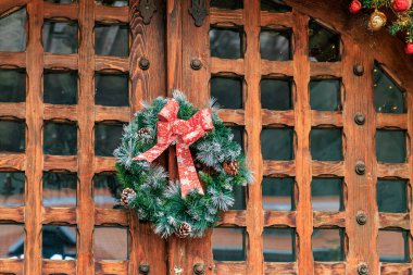 Kırmızı kurdeleli çelenk ahşap bir kapıda asılı. 15 Aralık 2024 Busteni Romanya.